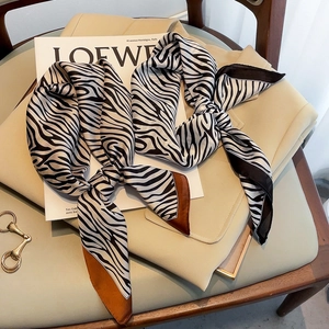 Detail of zebra print silk scarf on trench coat with brand magazine accessory