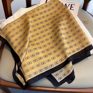 Detail view of ginger yellow silk scarf with black butterfly pattern on a chair