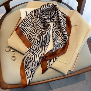 Elegant zebra print silk scarf with brown borders draped on a beige office blazer