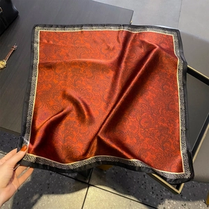 Elegante sciarpa in seta paisley rosso vintage con bordi dorati su fondo di legno