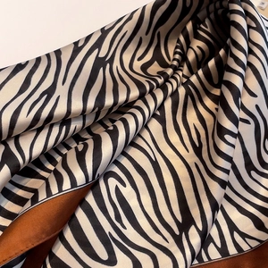 Close-up of zebra print silk scarf showing glossy satin texture and black-white pattern