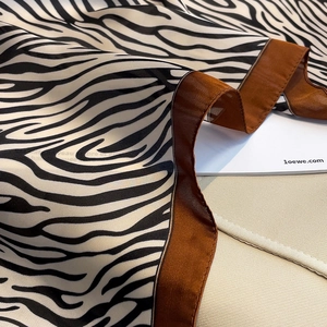 Detail of zebra print silk scarf with luxury bronze satin border and smooth texture