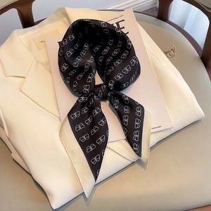 Elegant black and white silk scarf with bow pattern on a white blazer, French style
