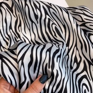 Detail shot of soft zebra print satin scarf fabric showing silky texture and black white stripes