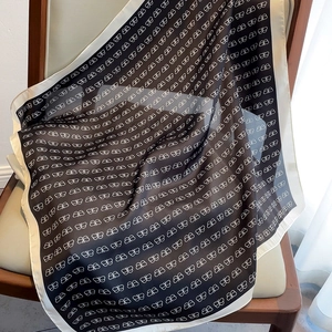 Detail of silk square scarf with butterfly logo print draped on a leather chair