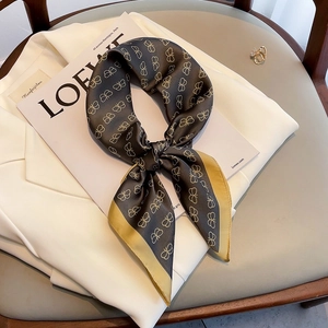 Elegant butterfly print silk scarf in taupe and gold styled on a white blazer coat