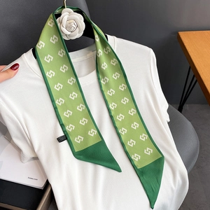 Macro detail of a green silk neck scarf with geometric patterns on a white t-shirt