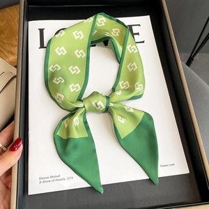 Macro view of green geometric silk scarf with interlocking patterns and satin texture