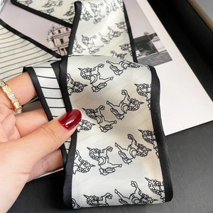 Close-up of a black and white silk twilly scarf with unicorn print and border