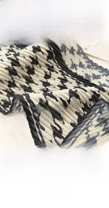 Détail d'un foulard en soie plissé pied-de-poule noir et blanc avec bordure soignée