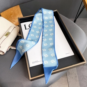 Detail of light blue silk scarf with white geometric patterns and pointed ends on magazine