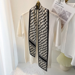 Détail d'un foulard étroit plissé à motif pied-de-poule noir et blanc sur tricot blanc