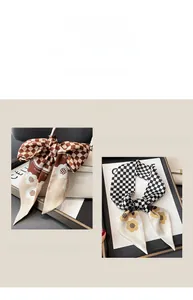 Detailansicht eines Seidenschals mit Schachbrettmuster und Blumen als Taschenaccessoire