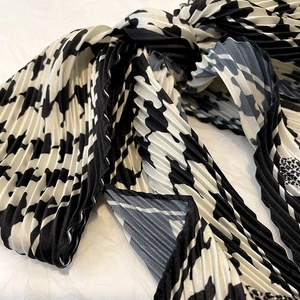 Gros plan sur un foulard en soie plissé à motif pied-de-poule noir et blanc élégant