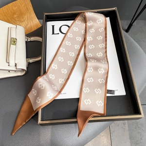 Detail of silk skinny scarf with geometric pattern displayed on a magazine and bag