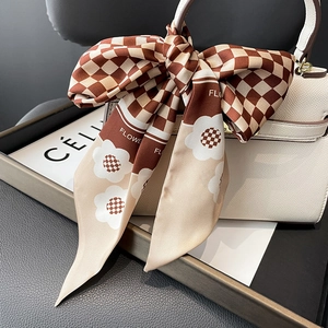 Langer Seidenschal mit Karomuster und Blumenmotiven als Schleife an weißer Handtasche