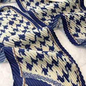 Détail macro du foulard en soie pied-de-poule avec texture plissée et bordure dorée