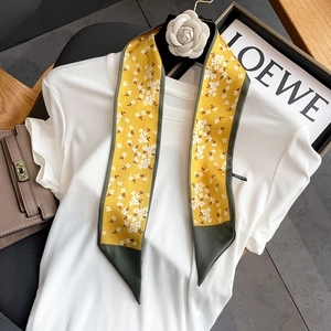 Detail of yellow floral skinny scarf tied on a white striped shirt with green contrast ends