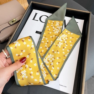 Detail of yellow floral skinny scarf showing white flower pattern and green contrast borders