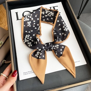 Floral skinny silk scarf in black and white with contrast tan border tied on a magazine