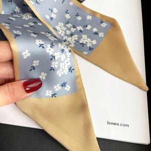 Detail of floral skinny scarf in light blue with white pattern and khaki border