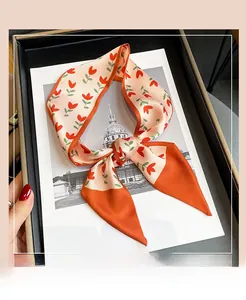 Détail d'un foulard étroit à fleurs avec tulipes rouges noué en boucle sur un coffret cadeau