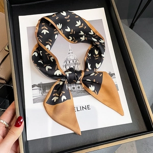 Vue détaillée d'une écharpe étroite en soie à motif tulipe nouée en ruban sur un coffret