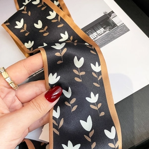 Détail d'un foulard étroit en soie à motif tulipe utilisé comme accessoire de sac chic