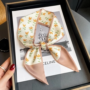 Foulard étroit en soie à motif tulipes avec extrémités roses sur un plateau chic