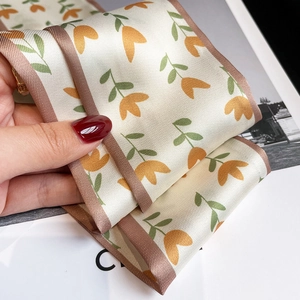 Gros plan du foulard en soie à motif de tulipes orange avec bordure marron chic