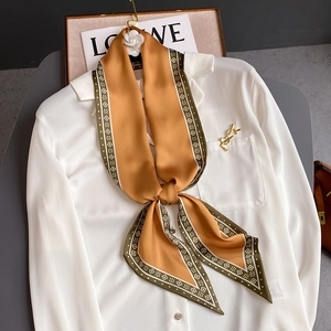 Eleganter orangefarbener Seidenschal mit geometrischem Rand an einer weißen Bluse
