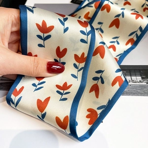 Gros plan d'un foulard mince en satin avec tulipes rouges et finition bleu marine