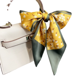 Floral satin skinny scarf in yellow and grey tied as a decorative bow on a handbag handle