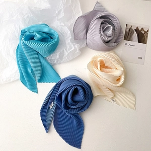Detailed view of assorted pleated skinny scarves in gradient blue, violet, and beige tones