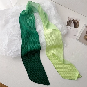 Detailed close-up of green gradient pleated scarf with fine accordion pleats texture