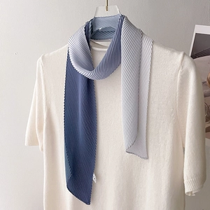 Detail of pleated gradient blue scarf showing fine organza texture on a knit top