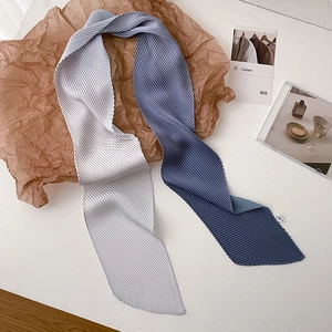 Detail of pleated silk scarves in gradient blue and grey on minimalist brown paper