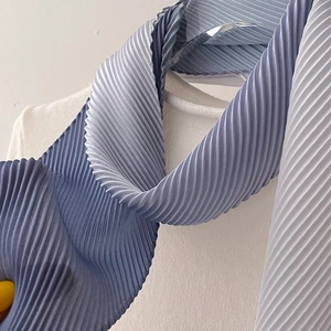 Close-up of pleated silk scarf with elegant blue-grey gradient and soft glossy texture
