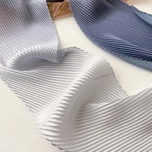Detail of silver grey and mist blue silk scarf with fine pleated texture and satin finish