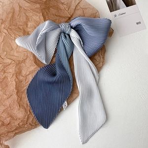 Detailed view of dual-tone pleated gradient bow hair accessory on vintage paper base