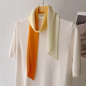 Close-up of pleated gradient silk scarf in orange and beige with wrinkled texture