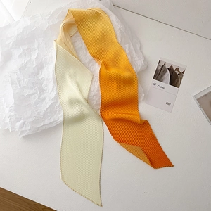 Detail of pleated skinny scarf featuring a yellow to orange gradient and delicate stitching