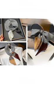 Classic houndstooth twilly scarf tied on a beige handbag with luxury chain patterns