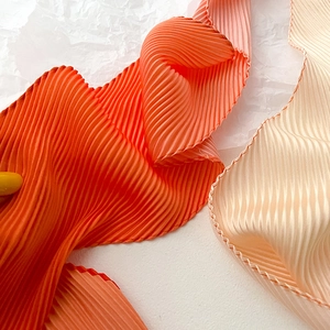 Detailed close-up of pleated texture on gradient orange chiffon scarf with fine pleats