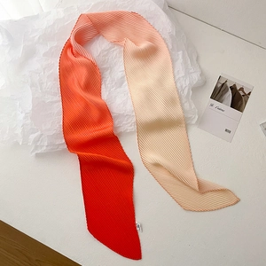 Detail of narrow pleated silk scarf with vibrant orange gradient and wrinkled texture