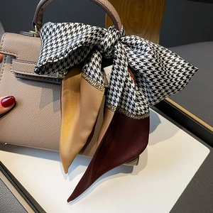 Detail of grey pebble leather handbag with houndstooth silk scarf on the handle