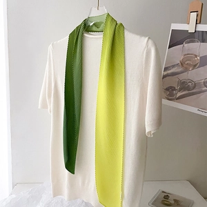 Detail of pleated silk scarf with gradient transition from deep green to soft yellow