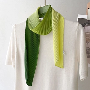 Detail of pleated silk scarf showing tri-color green gradient texture and vertical pleats