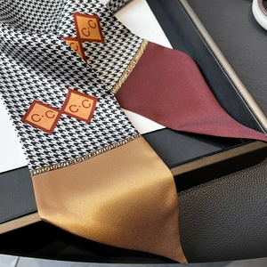Detailed view of houndstooth silk scarf with chain print and burgundy accents