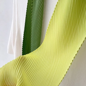Detail of elegant pleated gradient green scarf featuring fine accordion texture and folds